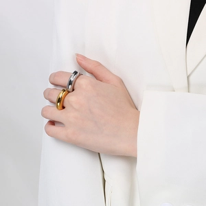 Close-up of chunky polished gold and silver rings worn together on a model's hand