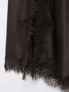 Makrodetail der seidigen Satinstruktur und exquisiten schwarzen Spitzenborte am Kleid