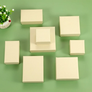 Top view of cream-colored square and rectangular cardboard jewelry gift boxes on green background