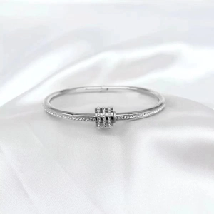 Silver stainless steel bangle with pave diamonds and three sliding ring charms on silk