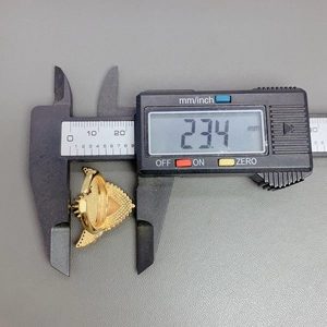 Detailed measurement of gold heart wings ring width with digital caliper at 23.4 mm