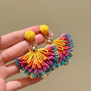 Detailed close-up of colorful handmade raffia fan-shaped earrings for summer vacation