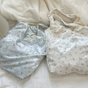 Macro detail of pearlescent bear print silk tote bags in light blue and cream white