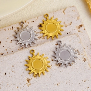 Detail view of gold and silver sun-shaped 304 stainless steel pendants on a stone slab
