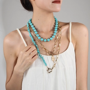 Close-up of triple-layered necklace with turquoise beads and gold embossed pendant