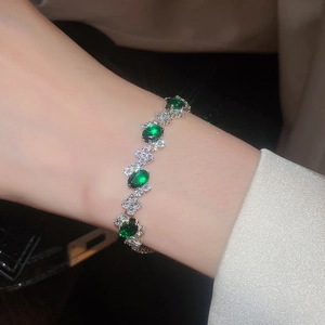 Detail shot of a silver bracelet featuring emerald green oval stones and white zircon
