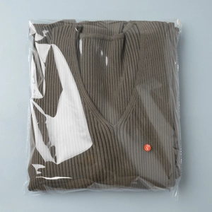 Detail view of the V-neck knit dress texture and S-size label inside the packaging bag