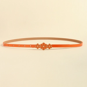 Detail of an orange skinny belt featuring three gold flower-shaped metal buckles