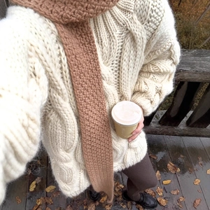 Women's cream white cable knit sweater with brown scarf shown from a top-down perspective