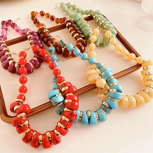 Détail de colliers de perles vintage colorées avec anneaux dorés sur un plateau en bois