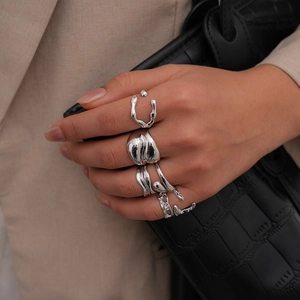 Set di 5 anelli metallici argento con geometria irregolare mostrati sulla mano