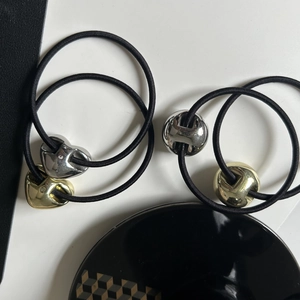 Close-up of high-elastic black hair ties with brushed gold and silver heart and ball charms