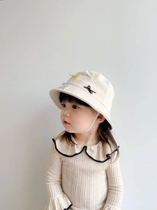Close-up of baby beige wave-collar knit sweater and cream sun bucket hat with bow