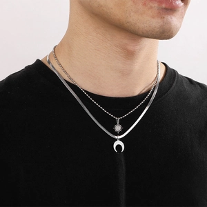 Detail of silver double-layered snake chain necklace with star and moon charms on a model