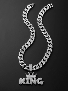 Macro shot of silver Cuban link chain with iced out crown KING pendant on black background