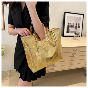 Detailed shot of golden crocodile pattern tote bag with metallic gloss and stylish charms