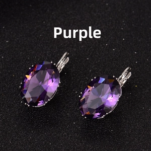 Detailed macro view of purplish red oval gemstone earrings with silver leverback closure