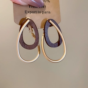 Détail de la texture bois naturel et finition dorée mate sur les boucles d'oreilles