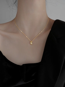 Close-up of minimalist gold teardrop pendant necklace on model's neck for elegant style