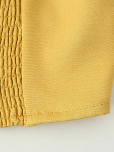 Detail von gelbem Smok-Gewebe und Twill-Struktur mit präzisen Nähnähten