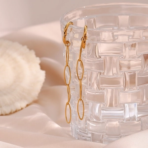 Close-up of 18K gold plated long oval link chain earrings hanging on a glass rim