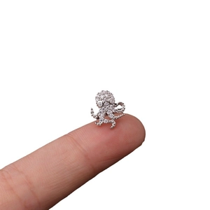 Exquisite silver octopus stud earring with zircons held on a fingertip for scale