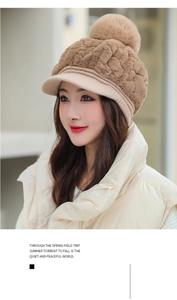 Detail of warm winter knit hat with a large brown faux fur pom pom and soft plush texture