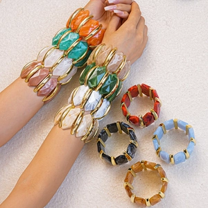 Gros plan de bracelets en résine acrylique colorée avec pièces dorées sur fond texturé