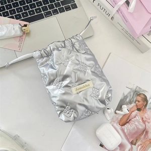 Close-up of silver quilted drawstring bag with bow embroidery and stylish metal finish