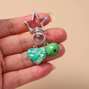 Detail of silver star clasp with green sequin heart pendant and small matching bell