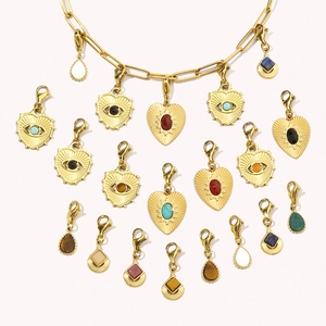 Detailed close-up of gold stainless steel heart and teardrop pendants with colorful stones