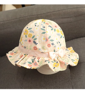 Detail of floral baby sun hat with pink bow and ruffled brim on soft beige cotton