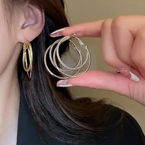 Three-layer nested silver needle hoop earrings with mixed smooth and woven metal textures