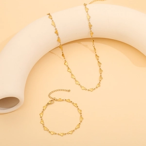 Detail of golden heart link necklace and bracelet set displayed on a neutral background