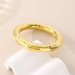 Detailed shot of 18k gold plated stainless steel bangle with hammered texture and gloss