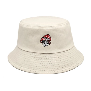 Beige cotton bucket hat with detailed red mushroom embroidery on minimalist white background