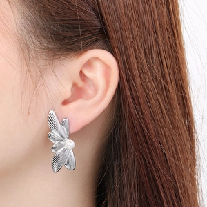Close-up of a silver butterfly pearl stud earring worn by a model for a stylish look