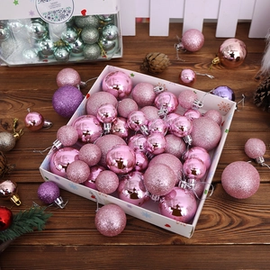 Pink and purple Christmas ornaments with glitter and matte finishes on a wooden table