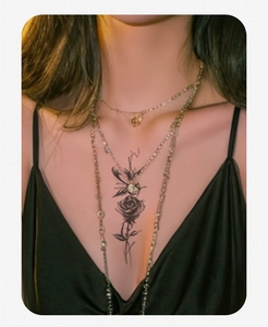 Close-up of a black rose floral temporary tattoo on a woman's collarbone with sharp details