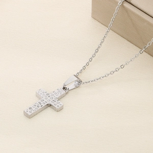 Detailed view of silver cross pendant with irregular hammered texture on thin chain