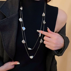 Collana doppia in metallo liquido argento con forme geometriche su maglione nero
