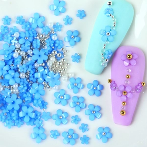 Detailed macro view of blue resin flowers with mixed gold and silver beads for nail art DIY