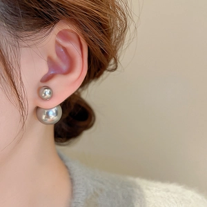 Close-up of elegant double pearl silver earrings worn on ear with high-gloss finish