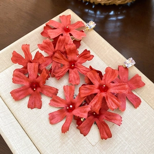 Detail of red fabric flower earrings with long tassels and sparkling zircon studs