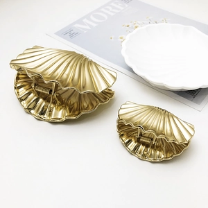 Elegant gold shell-shaped metal hair claws in two sizes displayed on white decor
