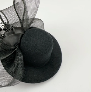 Detail of black mini top hat fascinator featuring delicate mesh veil and satin bow