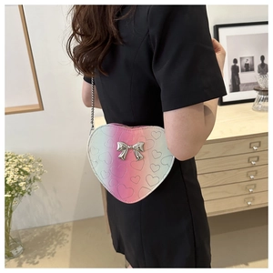 Detail of heart shaped crossbody bag with gradient pink and green colors and bow decoration