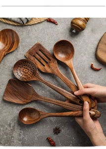 Macro shot of teak wooden kitchen utensil set with natural wood grain on stone background