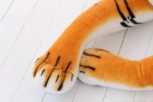 Close-up of tiger plush toy paws featuring orange striped fur and white stitched toes
