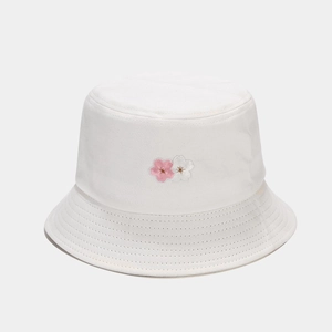 Detailed view of pink cherry blossom embroidery on a white cotton bucket hat